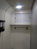 RV rental shower: compact white interior with mounted CONDITION and BODY WASH dispensers, overhead light, and towel bar.