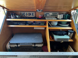 This organized rv rental kitchen galley features a cooler, camping stove, dishes, and spices, perfect for outdoor adventures.