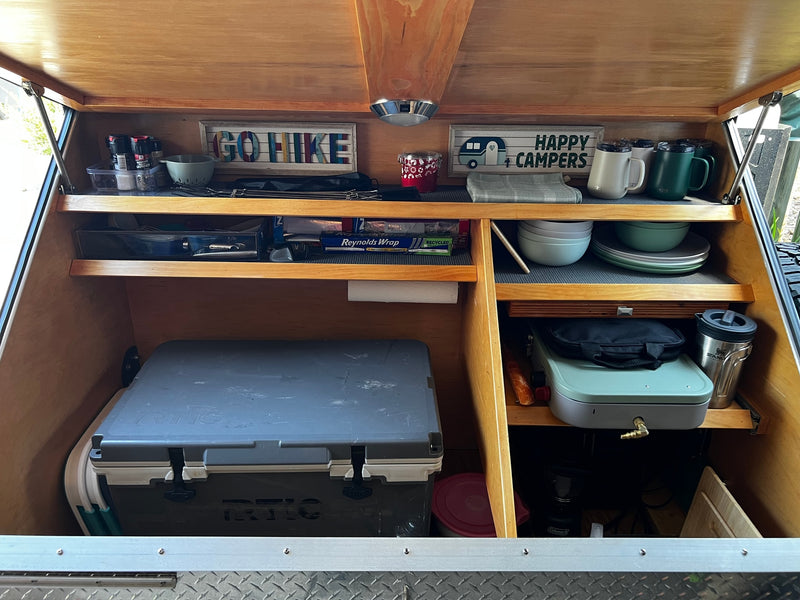 This organized rv rental kitchen galley features a cooler, camping stove, dishes, and spices, perfect for outdoor adventures. — photo 14