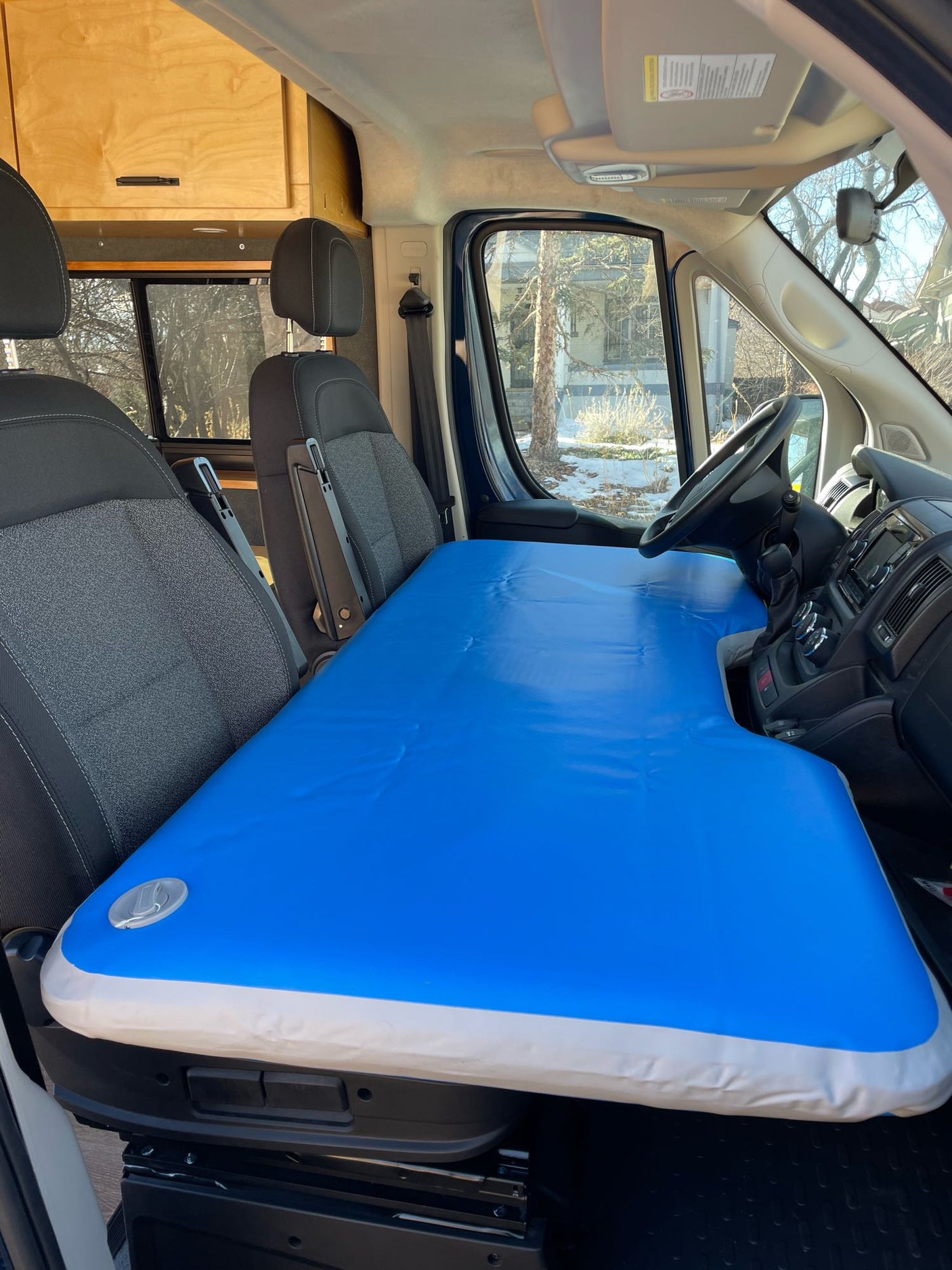This RV rental features an inflatable mattress turning front seats into a cozy bed. Perfect for van life adventures & camping!