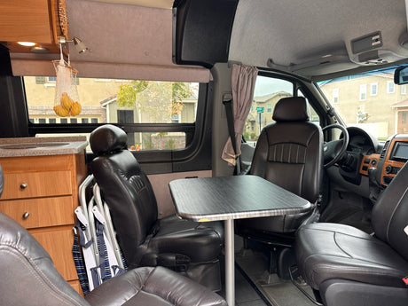 Spacious RV rental interior featuring a kitchenette, table, and black leather seating.