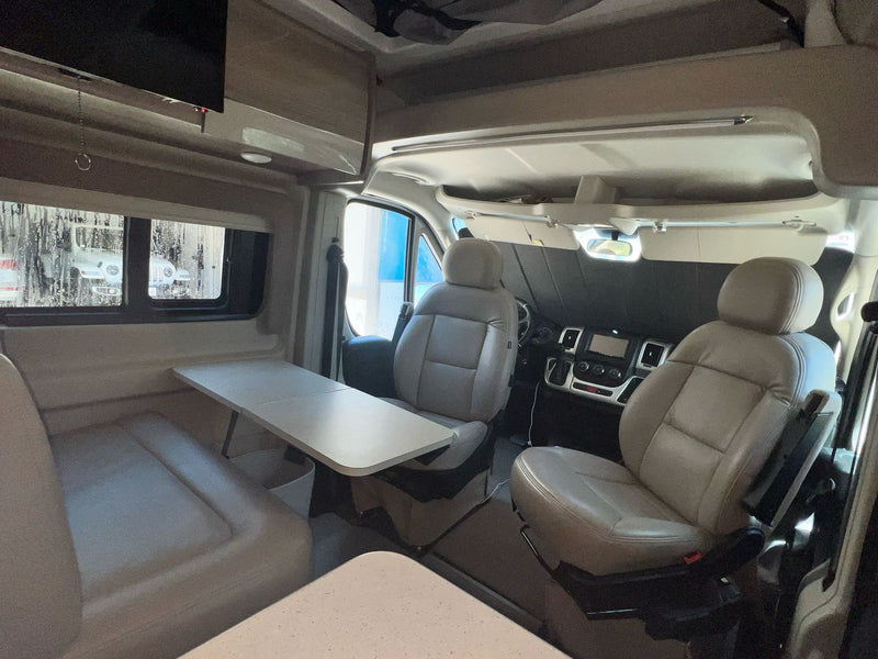 RV rental interior: cozy camper van living space with dining table, bench seating, and swivel front seats. — photo 7