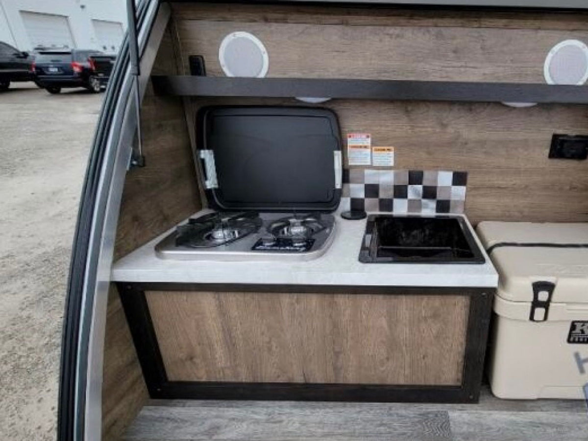 An RV rental's outdoor galley, showcasing a two-burner stove with griddle, sink, and large cooler. Ready for adventures. — photo 14