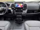 Modern RV rental interior: driver's view of the dashboard, large digital touchscreen, gear shifter, and front seats.