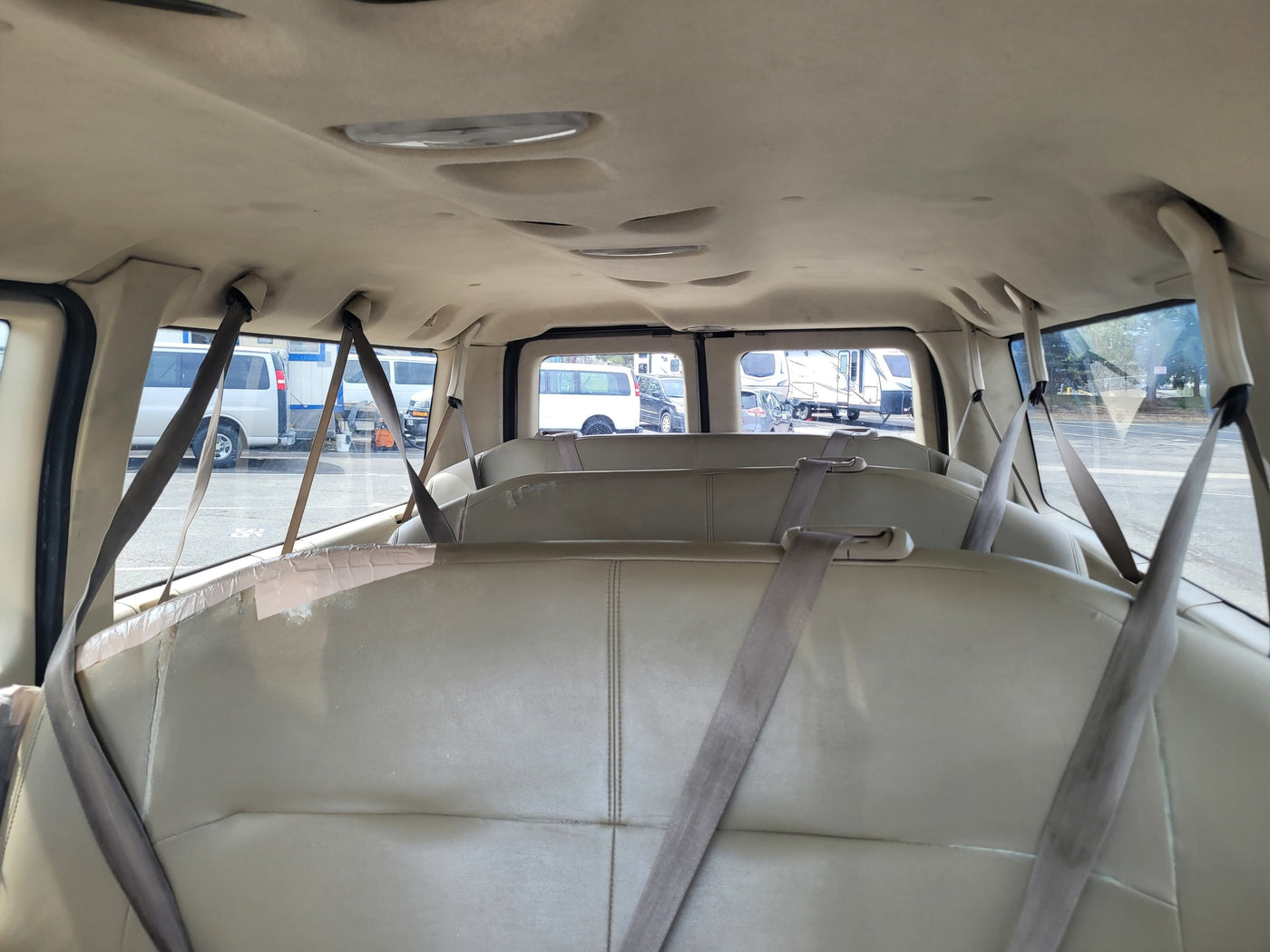 Spacious van interior with passenger seats & seatbelts, ideal for RV rental adventures. Other RVs are visible outside. — photo 5