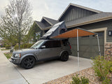 Gray Land Rover SUV with rooftop tent & side awning, an ideal rv rental alternative for overlanding and camping.