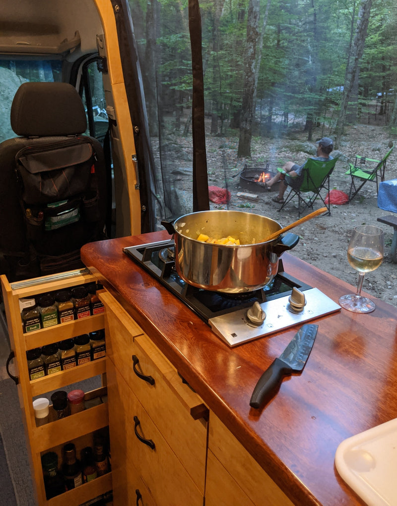 Cozy RV rental cooking: prepping dinner on the stove with a campfire view and a glass of wine. — photo 4