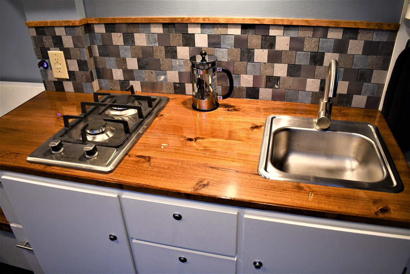 Efficient RV rental galley: wooden countertop, gas stovetop, sink, and mosaic tile backsplash. Compact and functional. — photo 9