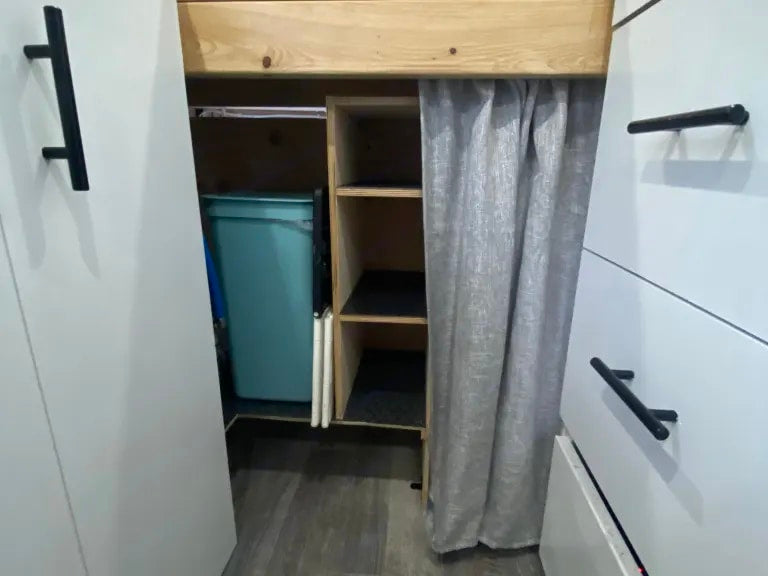 Inside an RV rental: smart storage solutions with shelving, a privacy curtain, and a tucked-away bin. — photo 14