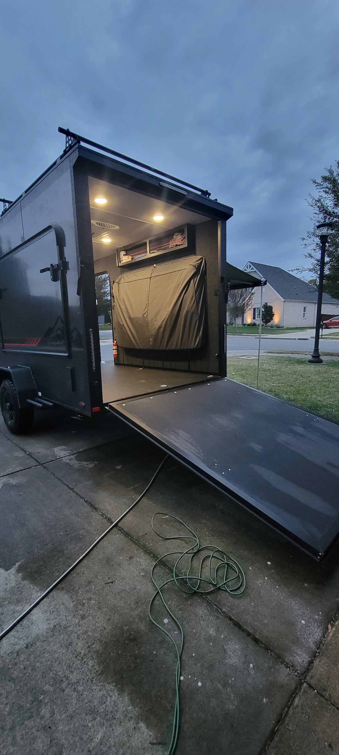 RV rental trailer: Rear ramp down, revealing a brightly lit interior with storage and covered bed, ready for adventure.