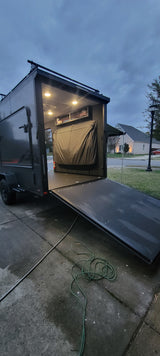 RV rental trailer: Rear ramp down, revealing a brightly lit interior with storage and covered bed, ready for adventure.