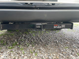 Back of an RV rental showing a black Curt trailer hitch receiver for towing. Gravel driveway below.