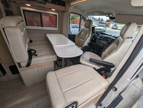 Comfortable RV rental interior showcasing beige seating, a movable table, and the front cabin area.