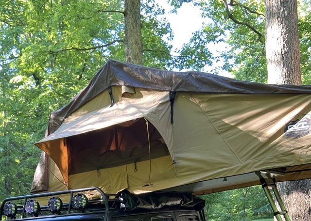 CVT rooftop tent fully opened on a roof rack in a wooded campsite