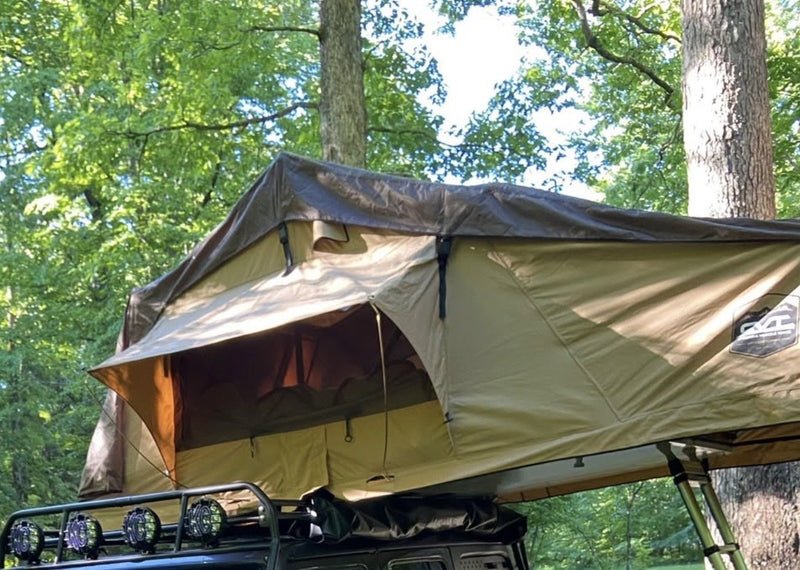 CVT rooftop tent fully opened on a roof rack in a wooded campsite — photo 1