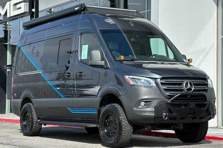 Dark gray Mercedes Sprinter **RV rental** van, off-road ready with large tires and roof lights.