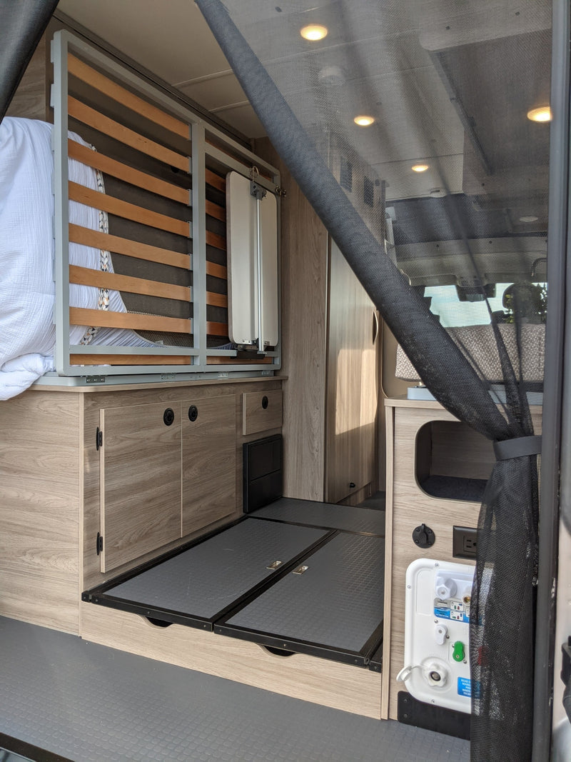  adjacent to a neatly made bed.|Modern RV rental: a compact kitchen setup with a stainless steel two-burner stove — photo 9