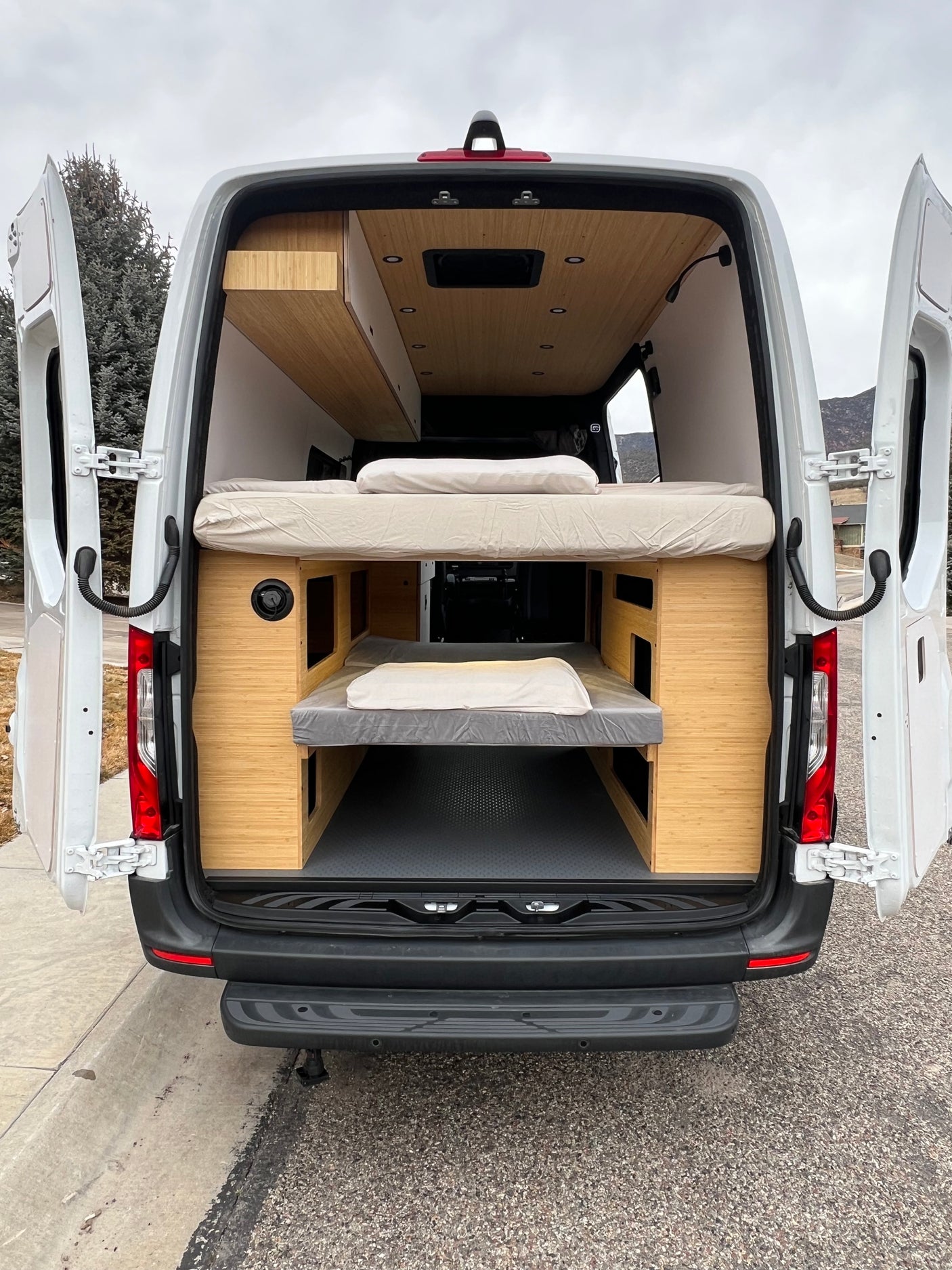 Explore in style! This RV rental camper van showcases its custom interior with two comfortable bunk beds and wooden paneling.