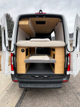 Explore in style! This RV rental camper van showcases its custom interior with two comfortable bunk beds and wooden paneling.
