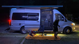 Enjoying a peaceful night in an RV rental. A silver Winnebago Boldt van is open, illuminated with cozy lights.