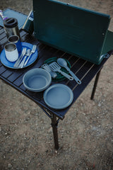 RV rental adventure: Coleman stove, camping dishes, & travel mugs on a portable table. Everything for outdoor cooking.