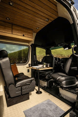 Experience comfort in this rv rental. A modern camper van interior with swivel seats, dining table, and wood ceiling.