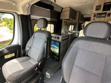 An rv rental interior showing front passenger seats, a well-equipped kitchenette with sink and fridge, plus overhead controls.