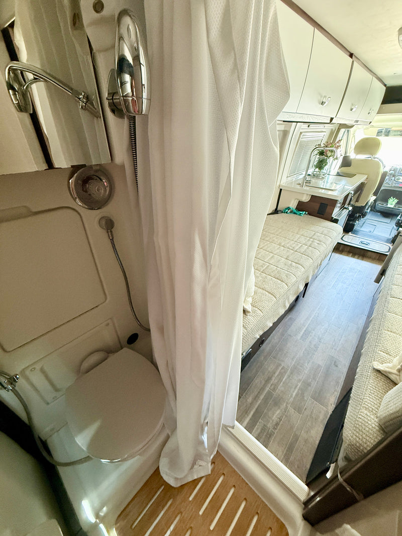 RV rental interior: A compact wet bath with toilet & shower, transitioning to the cozy living and sleeping area. — photo 8