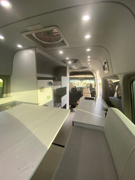 Spacious RV rental interior featuring a modern kitchen, bright lighting, and integrated bunk beds.