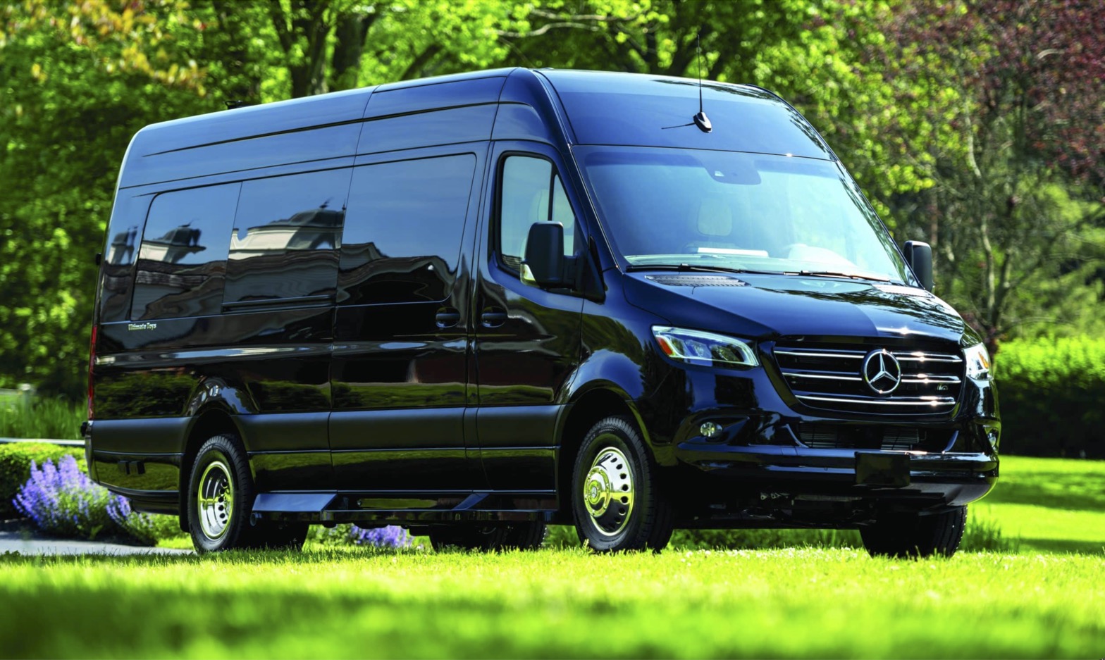 Black Mercedes-Benz Sprinter van on a lush green lawn. Ideal for a spacious and luxurious RV rental experience.