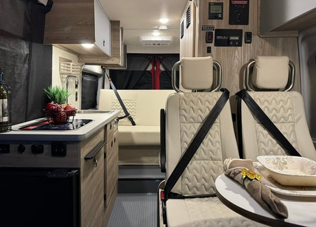 Step into this RV rental! A compact camper van interior with kitchen, comfy seating, and controls for travel.