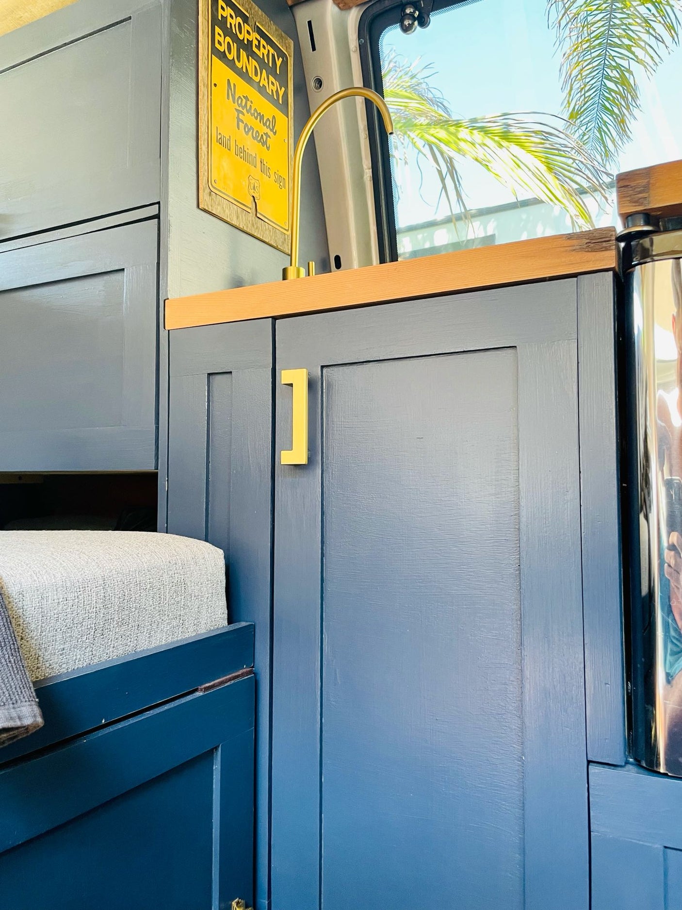 Stylish RV rental interior with blue cabinetry, a brass faucet, and wood accents. Enjoy comfy travels!