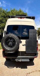 Experience an rv rental: This Storyteller Overland adventure van's rear view shows a large spare tire, gear panel, and rooftop awning.