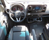 Inside a Mercedes-Benz Sprinter RV rental: view of driver's area with steering wheel, modern dash, screen, and cup holders.