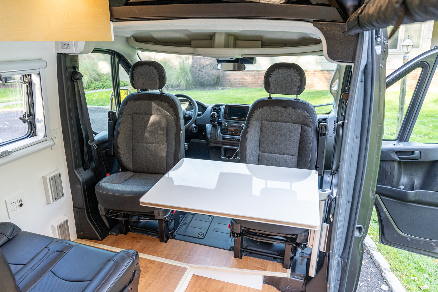RV rental interior featuring rotating front seats, a dining table, and the driver's area for a comfortable journey.