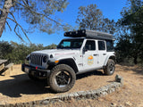 White Jeep Wrangler Rubicon 4x4 with rooftop tent, perfect for an RV rental overlanding or camping trip.