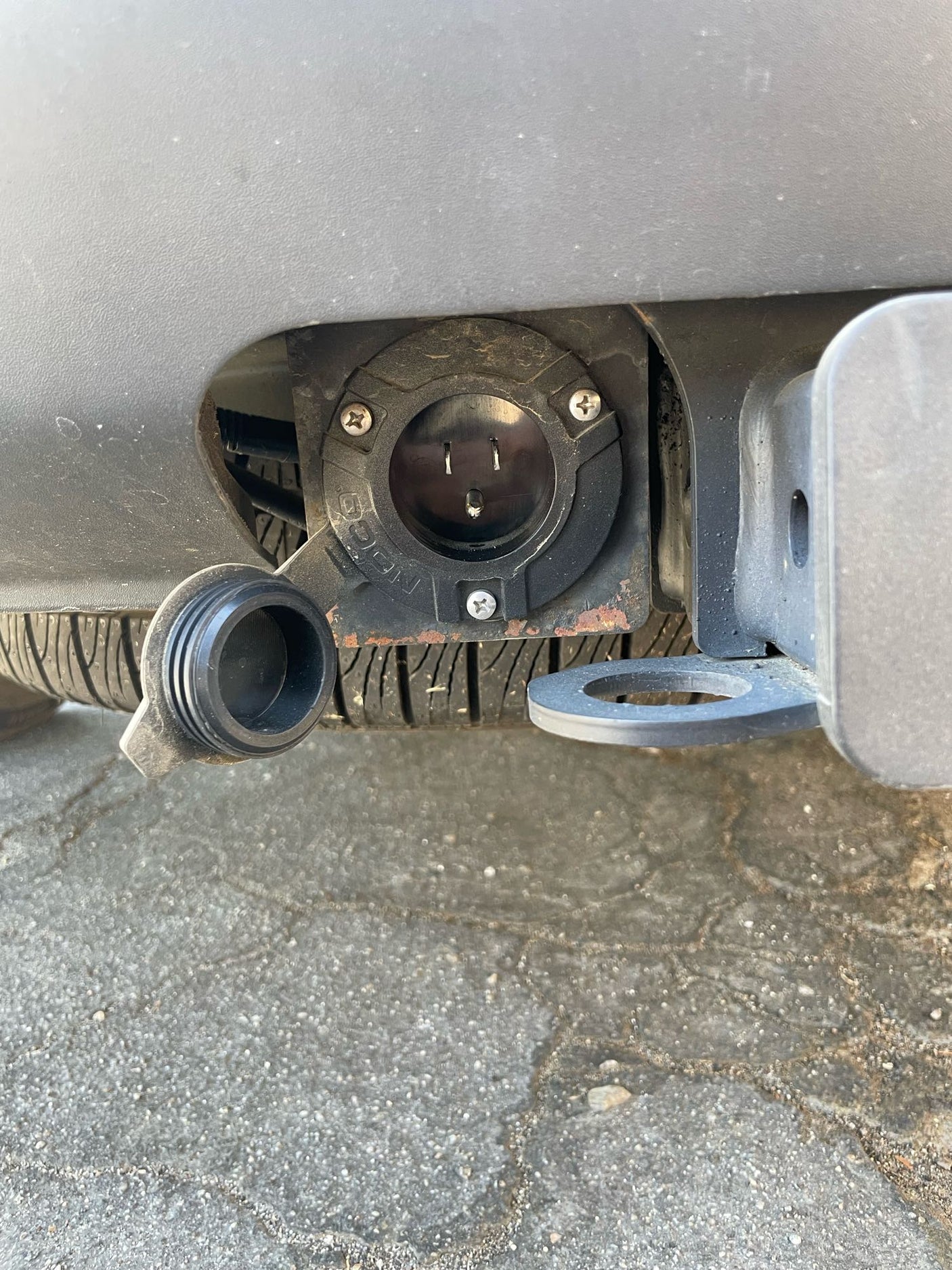 Close-up of an RV rental's rear bumper, featuring a 120V electrical outlet and tow hitch. Connect for auxiliary power.