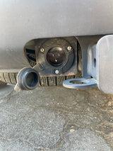 Close-up of an RV rental's rear bumper, featuring a 120V electrical outlet and tow hitch. Connect for auxiliary power.