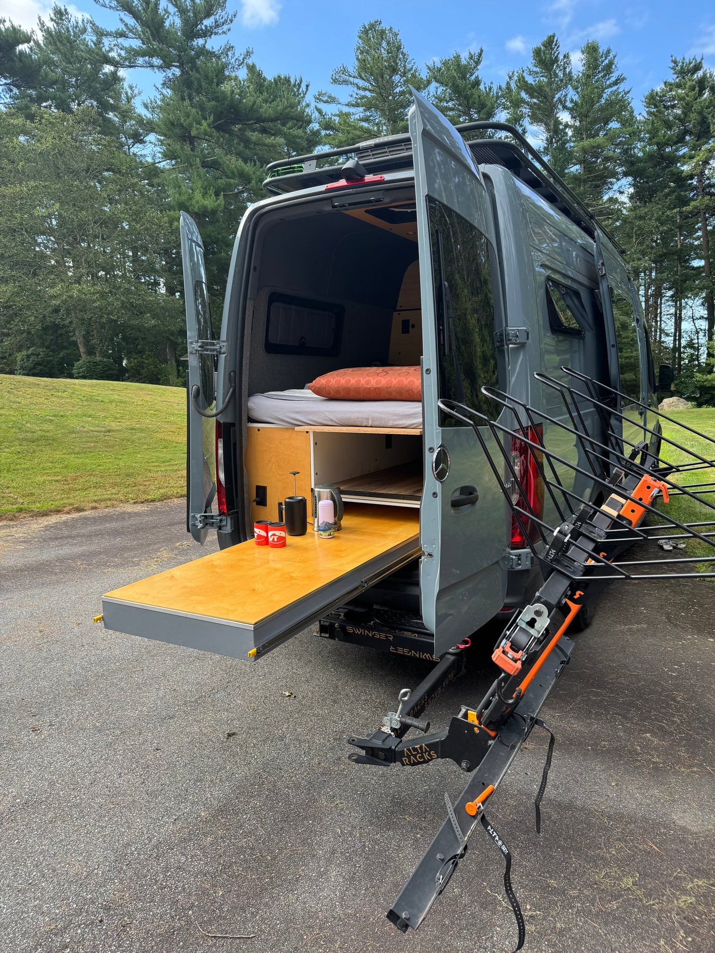 This gray RV rental is a custom camper van with an interior bed, slide-out table, and rear bike rack for outdoor adventures.