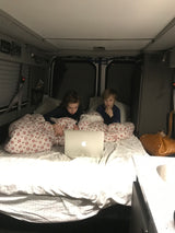 Inside an RV rental, two boys watch a laptop in their bed. A cozy setup for family travel.