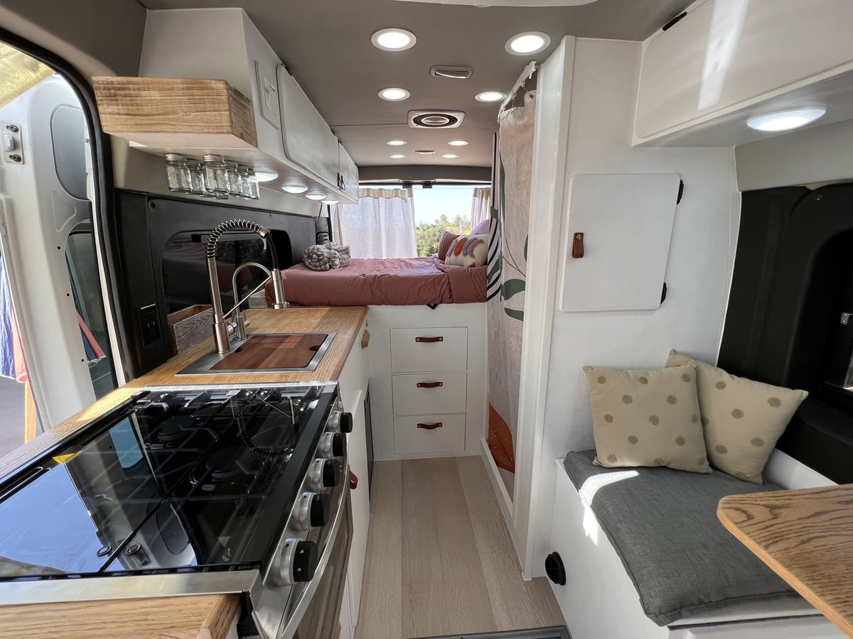 This modern rv rental interior features a compact kitchen with a sink and stovetop