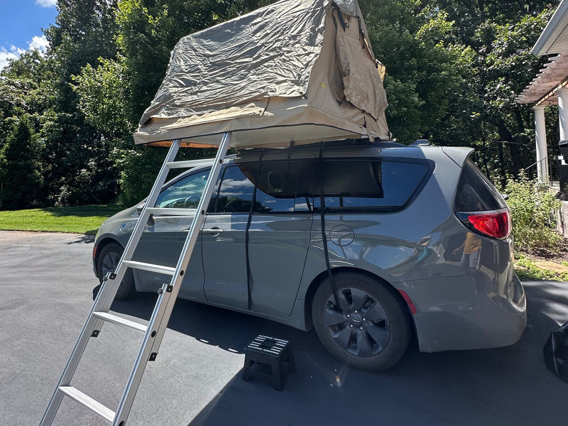 This gray minivan with a roof-top tent deployed and ladder on a driveway offers a great camping experience — photo 1