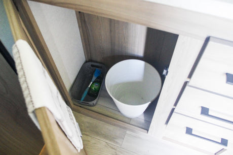 Efficient under-sink storage in this RV rental! Features cleaning supplies in a basket & a small trash bin.