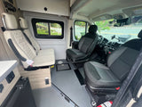 Spacious RV rental interior, showcasing comfortable quilted seating, driver's cabin, and textured floor.