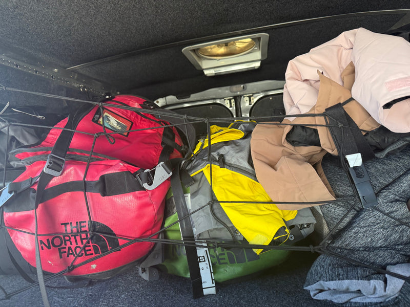 RV rental interior: A cargo net secures colorful North Face and Yeti duffel bags, jackets, and gear. — photo 7