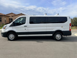 A pristine white van with dark tinted windows and rooftop vents/racks, possibly an RV rental, parked on a residential street.
