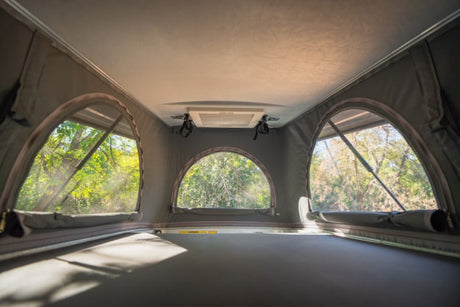 Spacious RV rental pop-top with scenic views. Enjoy nature through arched windows from a comfy sleeping area.