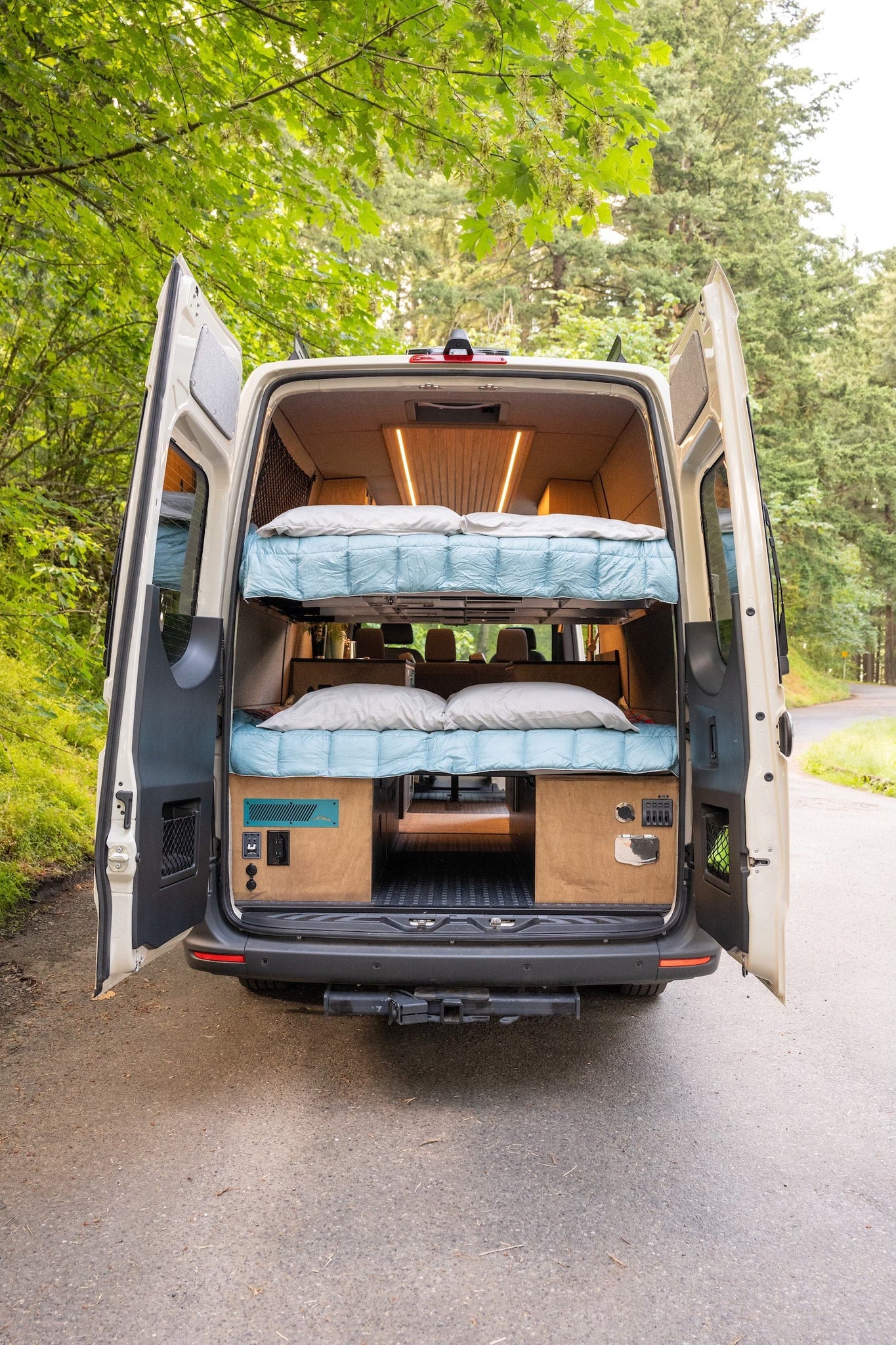 Rear view of an rv rental camper van, showcasing a custom-built interior with two cozy bunk beds and wood finishes. — photo 4
