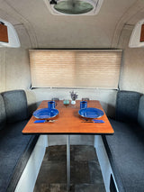 Cozy RV rental dinette area featuring a set table for two with blue plates, mugs, and decor. Ideal for travel.