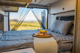 Relax and enjoy your RV rental with a cozy bed, chessboard, and a beautiful field view through the screened back doors.